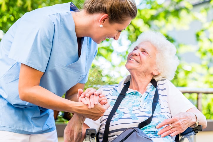 Respite care giver holding hand of senior woman on her patio