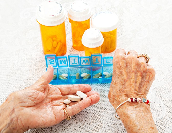 Closeup view of an eighty year old senior woman's hands as she sorts her prescription medications